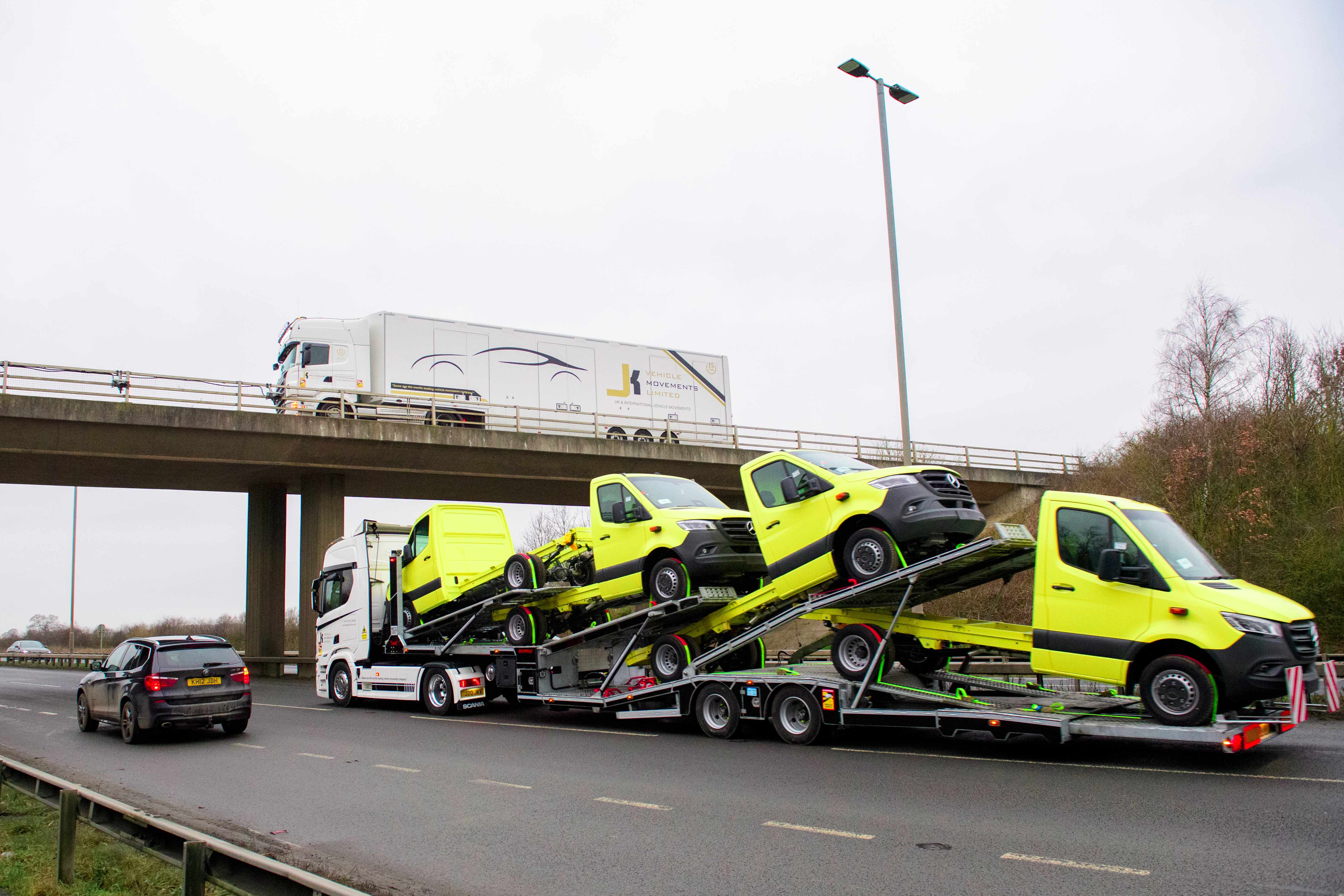 JK Vehicles transporting yellow vans on highway